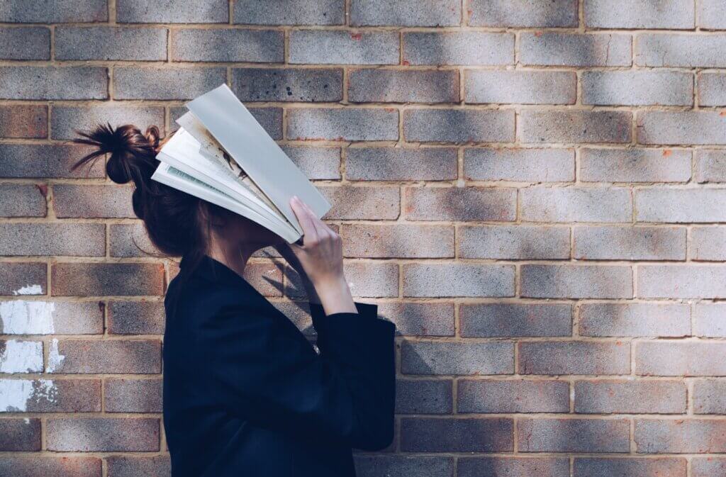 Image of a woman with a book on her face.
